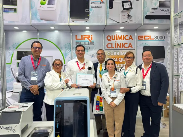 Equipo reunido junto a equipos de diagnóstico en un stand de exposición