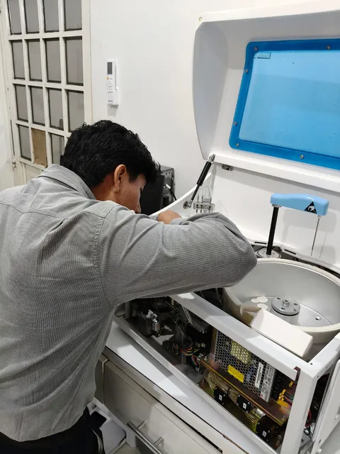 Técnico revisando el interior de un analizador de laboratorio